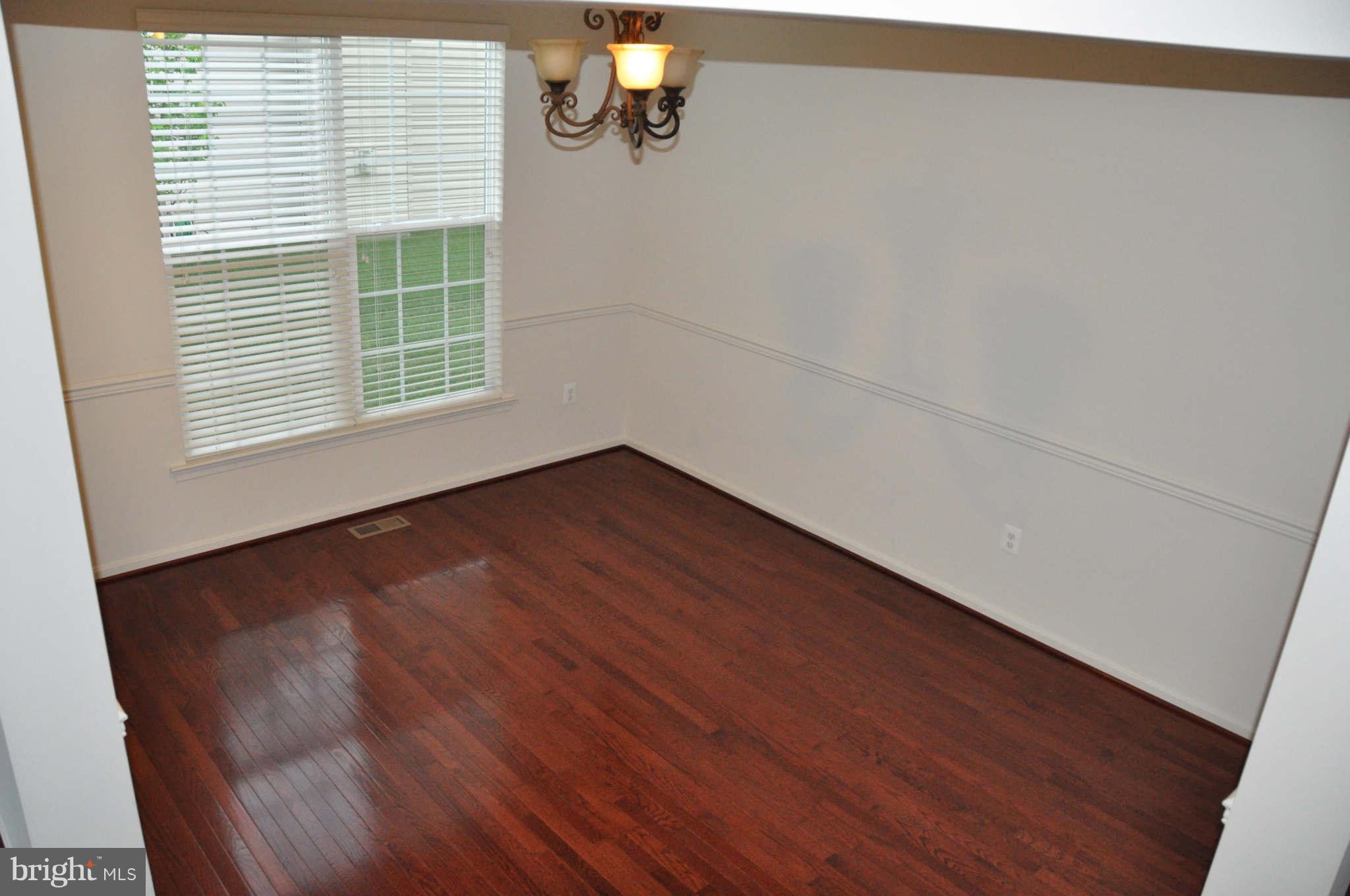 6627 Pebble Brooke Road Baltimore, MD 21209 - Photo 4 of 12 an empty room with wooden floor and windows