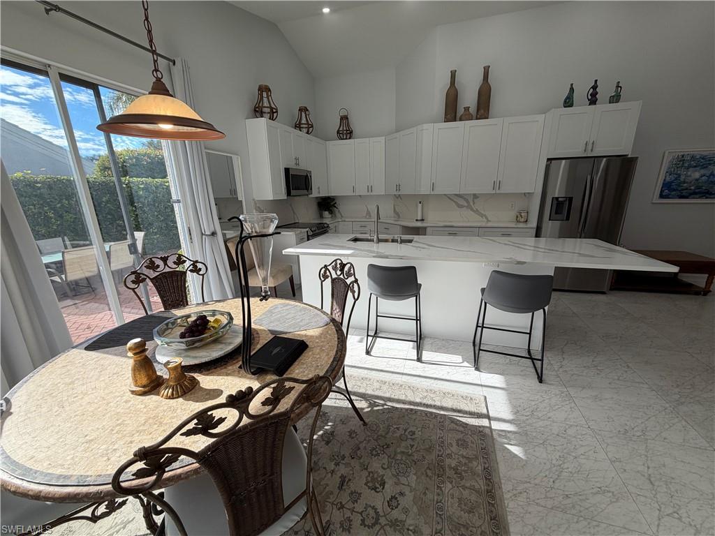5950 Almaden Drive Naples, FL 34119 - Photo 11 of 41 a kitchen with a table chairs and a wooden floor