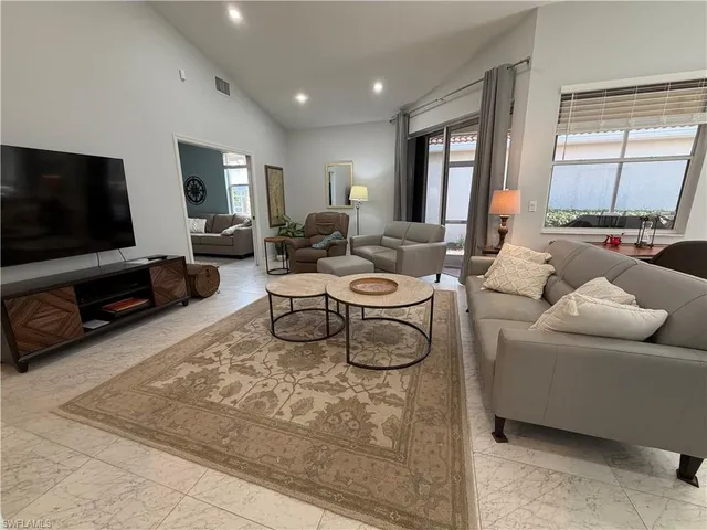 a living room with furniture a flat screen tv and a window