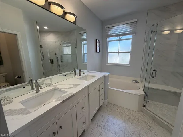 a bathroom with a tub double sink shower and mirror