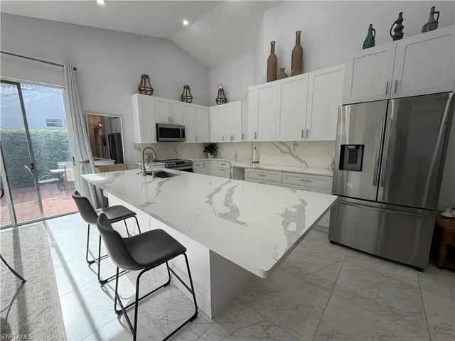 a kitchen with stainless steel appliances granite countertop a refrigerator a stove a sink a dining table and chairs