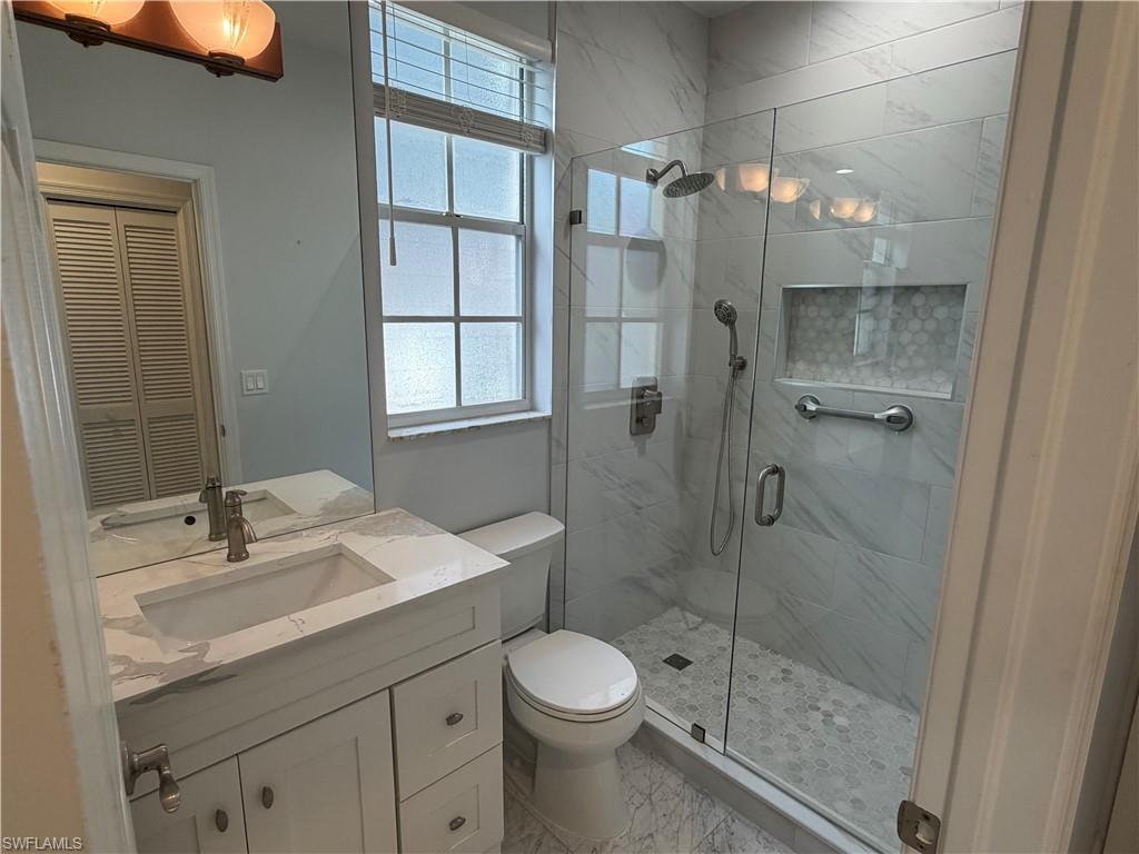 5950 Almaden Drive Naples, FL 34119 - Photo 33 of 41 a bathroom with a shower sink vanity and toilet