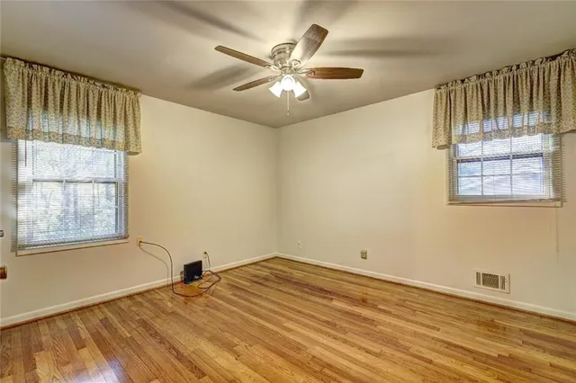 a view of empty room with wooden floor and fan