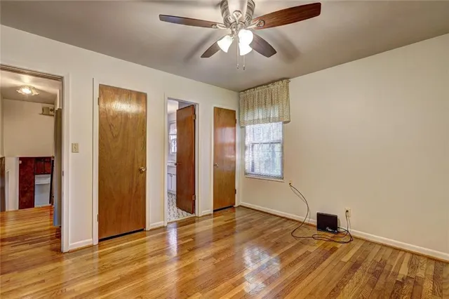 a view of an empty room with window and wooden floor