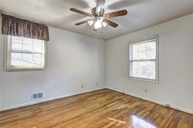 a view of empty room with wooden floor and fan