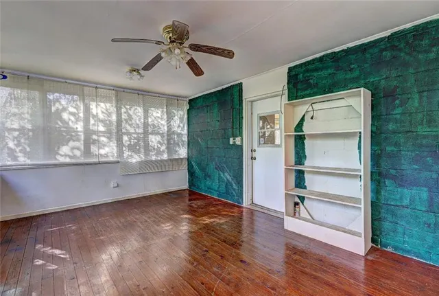 a view of an empty room with a window and wooden floor