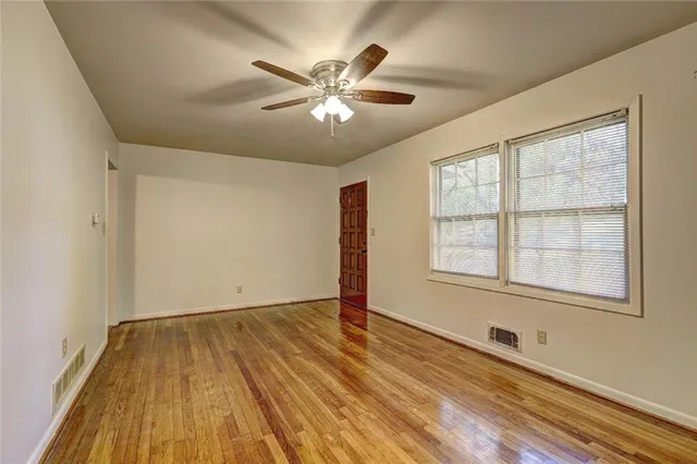 a view of an empty room with wooden floor and a window