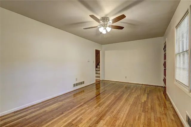 a view of an empty room with wooden floor and a window