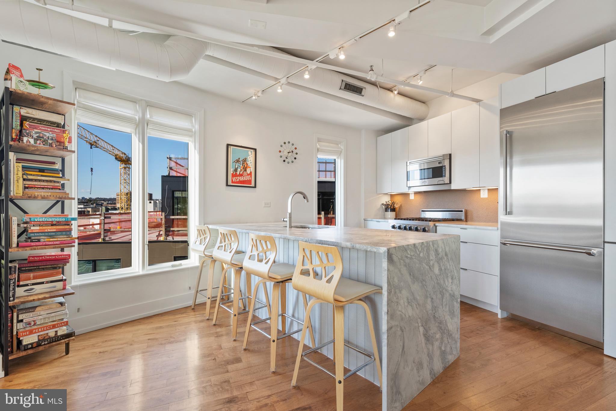 1700 Kalorama Road Northwest, Unit PH502 Washington, DC 20009 - Photo 10 of 50 a kitchen with stainless steel appliances kitchen island granite countertop a refrigerator a stove a dining table and chairs with wooden floor