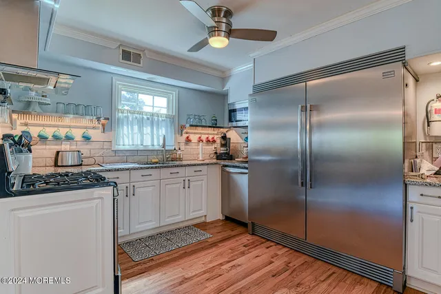 a kitchen with stainless steel appliances granite countertop a refrigerator a sink and white cabinets
