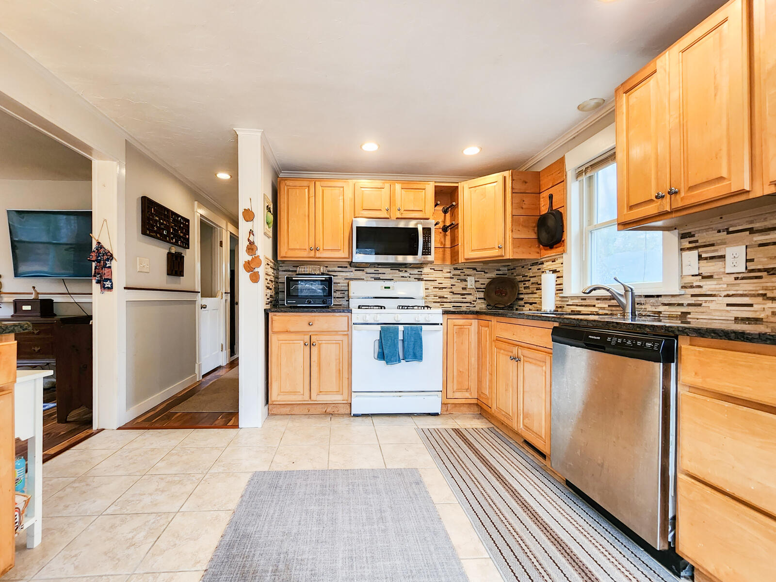 437 Cotuit Road Mashpee, MA 02649 - Photo 8 of 30 a kitchen with stainless steel appliances granite countertop a stove top oven a sink dishwasher a refrigerator and white cabinets with wooden floor