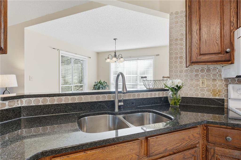 2240 McBrayer Court Cumming, GA 30028 - Photo 14 of 35 a kitchen with granite countertop a sink and a wooden cabinets