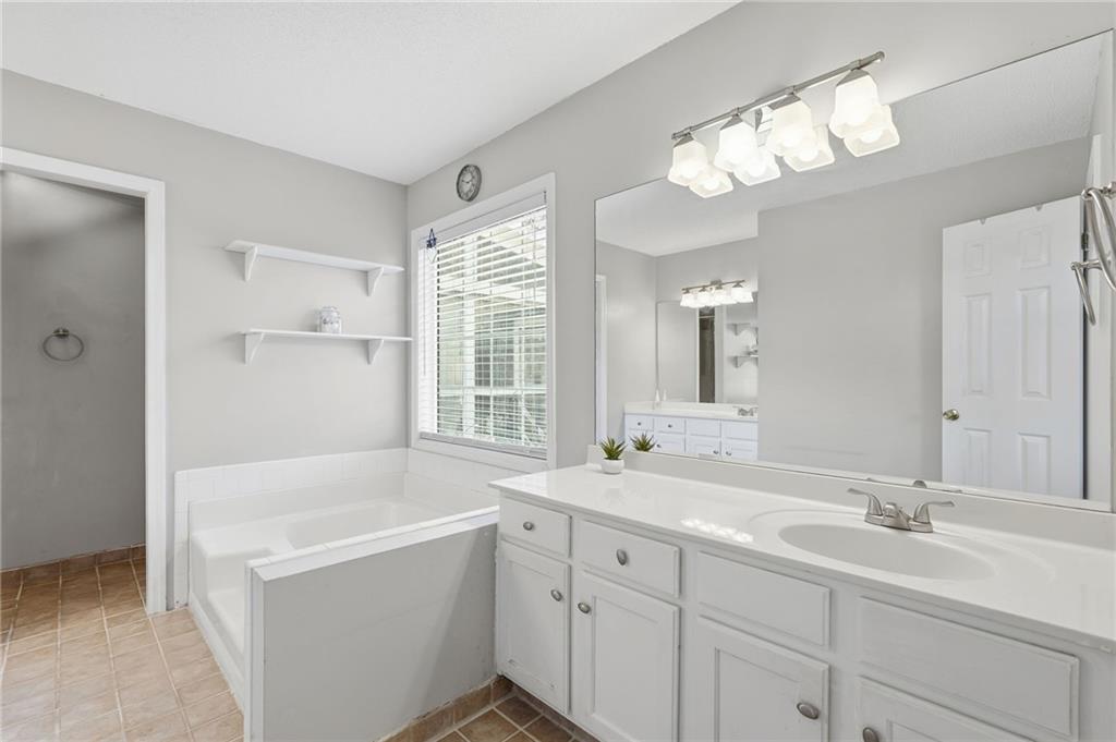 2240 McBrayer Court Cumming, GA 30028 - Photo 18 of 35 a bathroom with a tub a sink double vanity and a mirror
