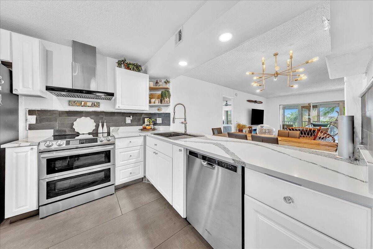 1523 East Hillsboro Boulevard, Unit 531 Deerfield Beach, FL 33441 - Photo 9 of 71 a kitchen with kitchen island a sink and white cabinets