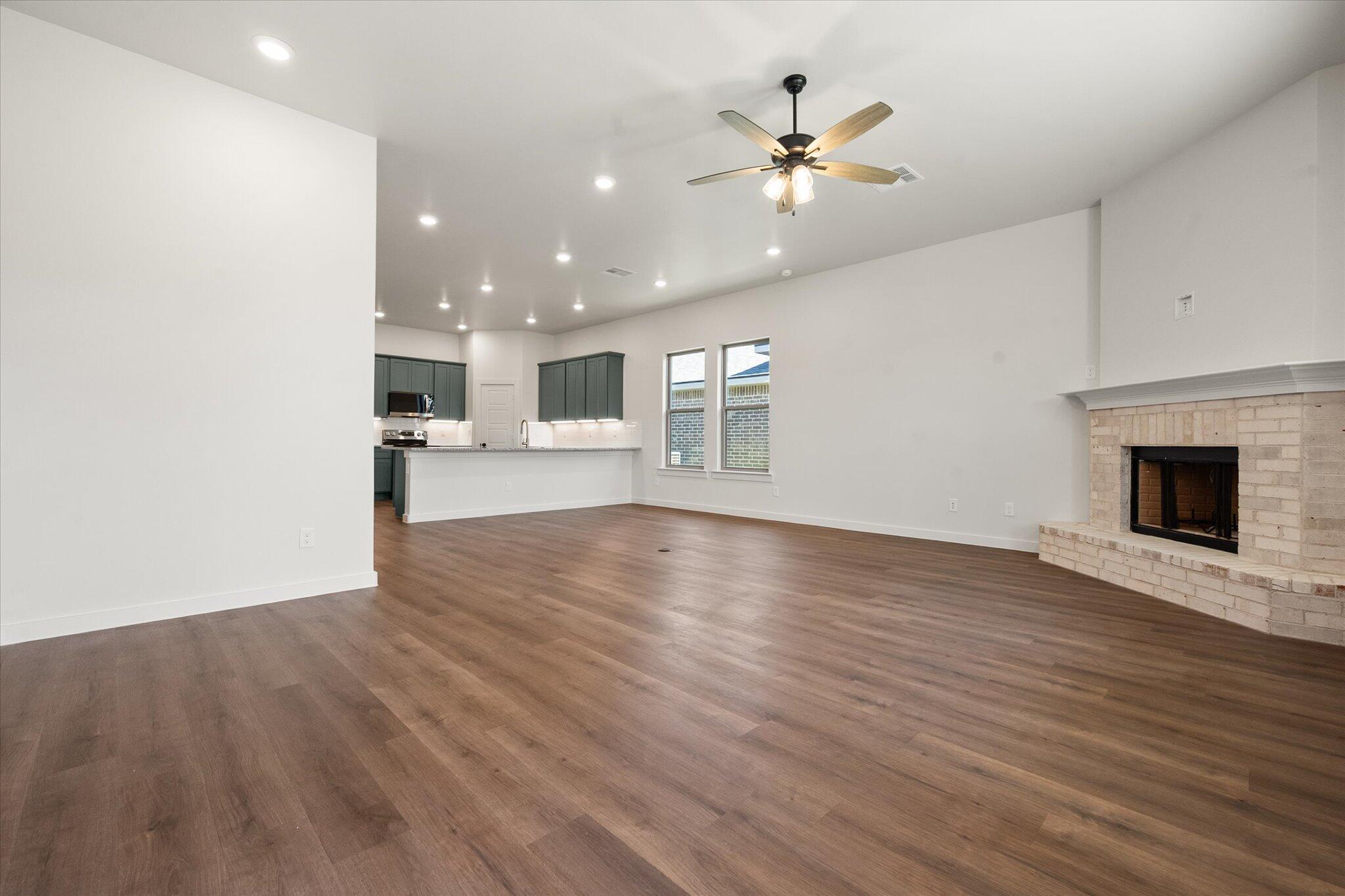 7007 16th Street Lubbock, TX 79416 - Photo 11 of 24 an empty room with wooden floor and fireplace