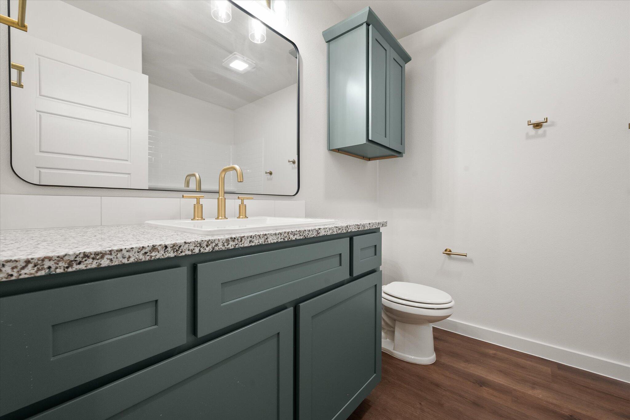 7007 16th Street Lubbock, TX 79416 - Photo 21 of 24 a bathroom with a granite countertop toilet sink and mirror