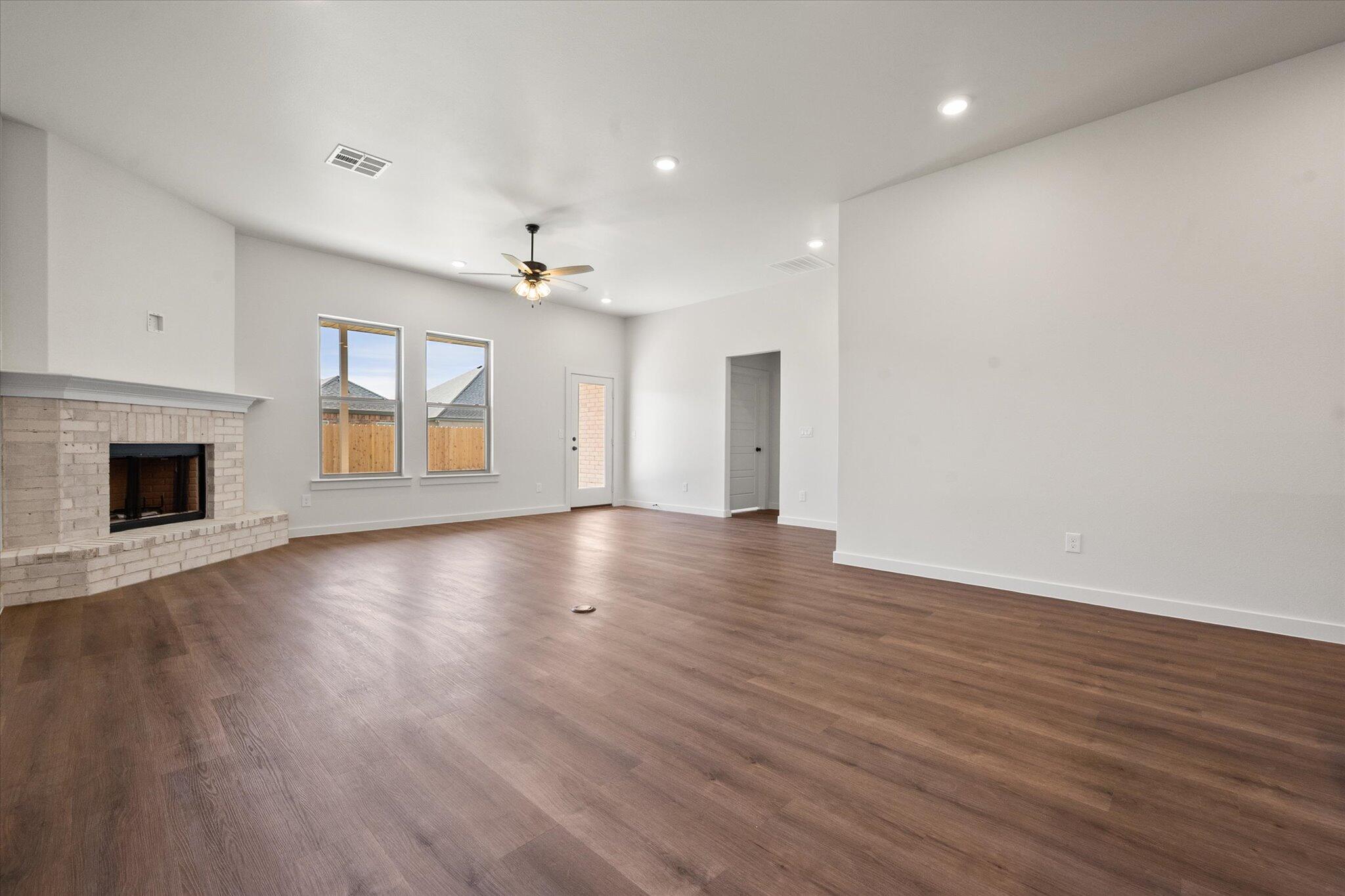 7007 16th Street Lubbock, TX 79416 - Photo 9 of 24 an empty room with wooden floor fireplace and windows