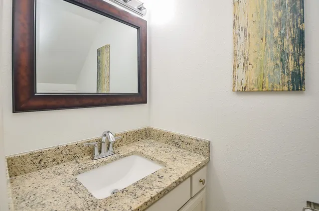 a bathroom with a granite countertop sink and a mirror