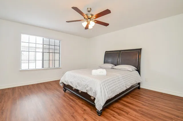 a bedroom with a large bed window and a ceiling fan