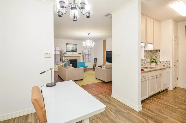 a living room with kitchen island white cabinets and wooden floor