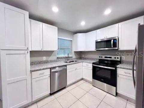 a kitchen with granite countertop white cabinets and stainless steel appliances