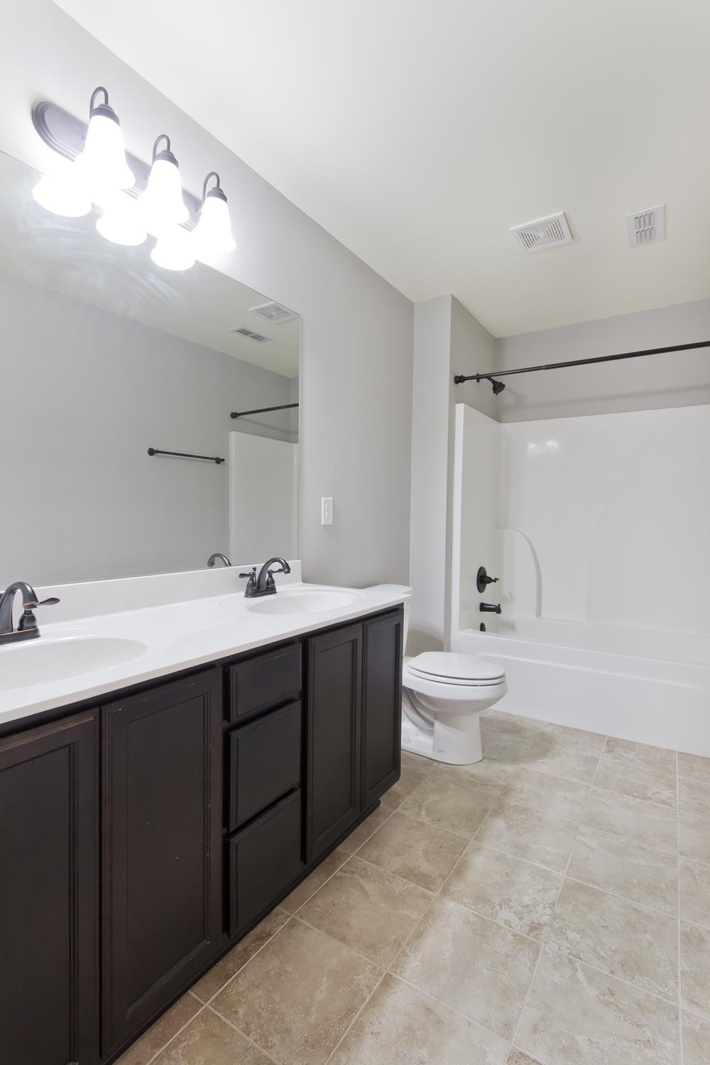 1011 Kyle Road Spring Hill, TN 37174 - Photo 28 of 30 a bathroom with a double vanity sink toilet mirror and shower