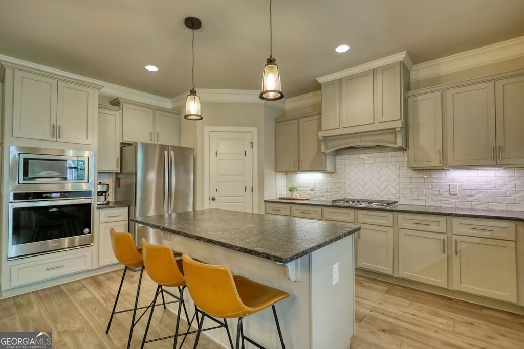 83 Bella Drive Monroe, GA 30655 - Photo 5 of 33 a kitchen with stainless steel appliances granite countertop a sink a stove a refrigerator and island with wooden floor