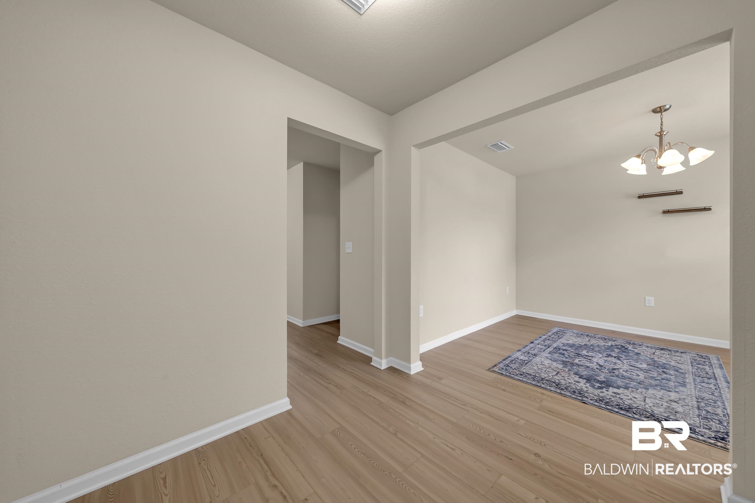 1704 Abbey Loop Foley, AL 36535 - Photo 5 of 38 Open-concept interior featuring light wood-finish flooring, neutral wall tones, white baseboards, and an elegant chandelier
