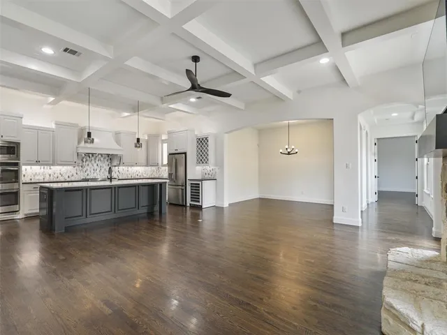 a large white kitchen with a white countertops a stove and a ceiling fan