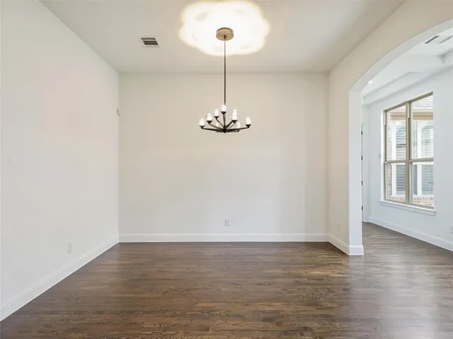 a view of a room with wooden floor chandelier and windows