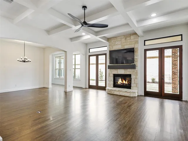 an empty room with wooden floor fireplace and windows