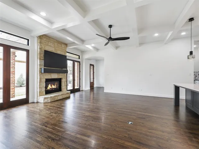 an empty room with wooden floor fire place and windows