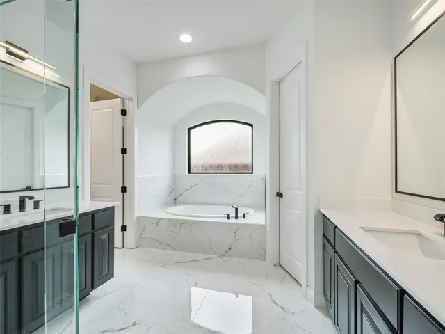 a spacious bathroom with a tub sink and mirror