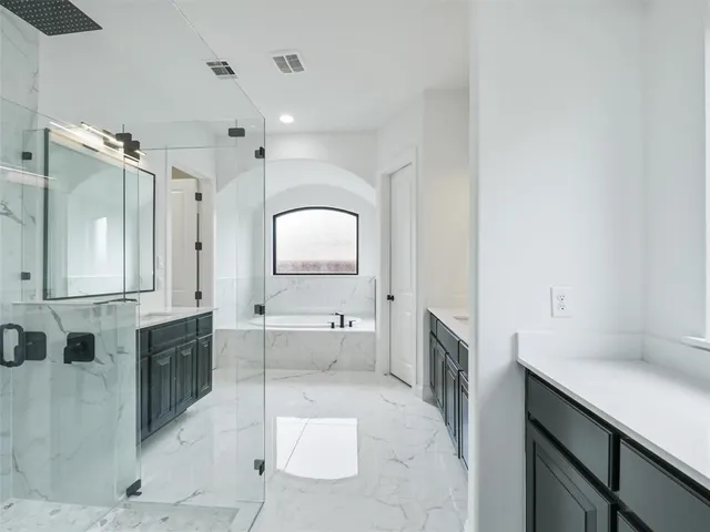 a large bathroom with a tub a double vanity sink a mirror and a shower