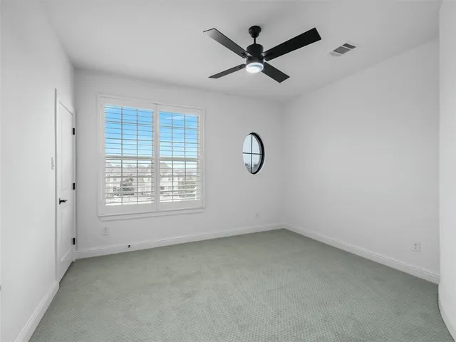 an empty room with a window and a fan