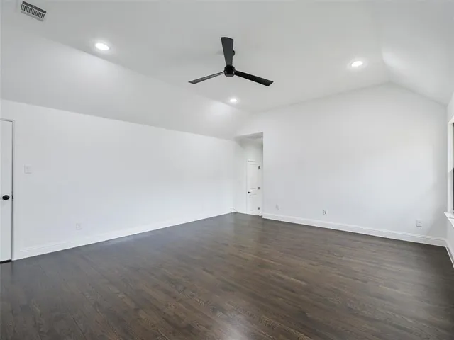 an empty room with wooden floor and ceiling fan