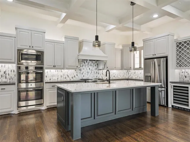 a kitchen with stainless steel appliances granite countertop a sink a stove a refrigerator and a wooden floor