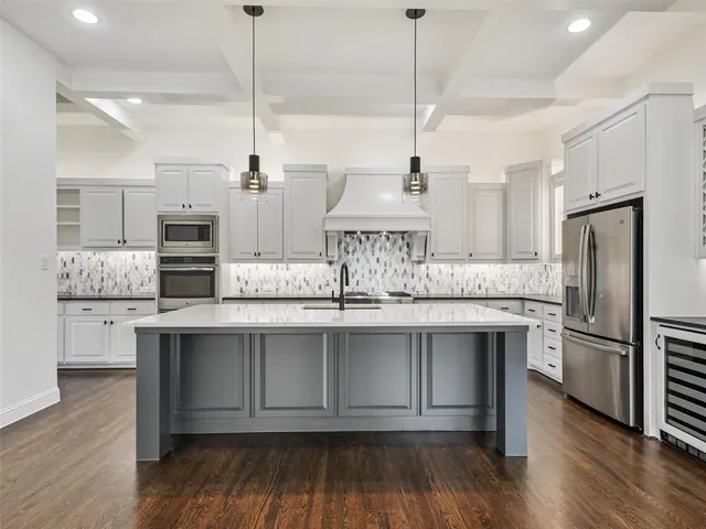 a kitchen with stainless steel appliances granite countertop a sink a stove a refrigerator and island with wooden floor