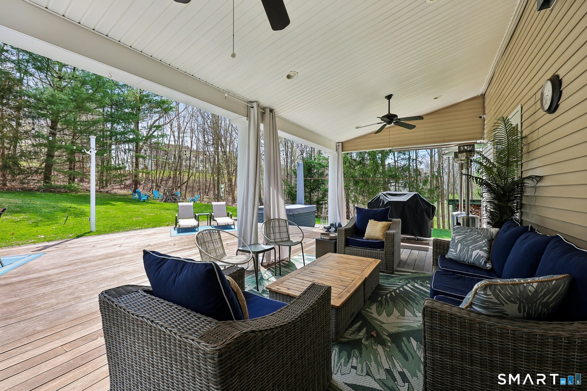 3 East Lake Road Danbury, CT 06811 - Photo 34 of 37 The back deck and patio showcase luxury decking and a thoughtfully designed outdoor layout, offering spaces for shade and sunning, a hot tub, firepit, and a grassy backyard ideal for relaxing and entertaining.