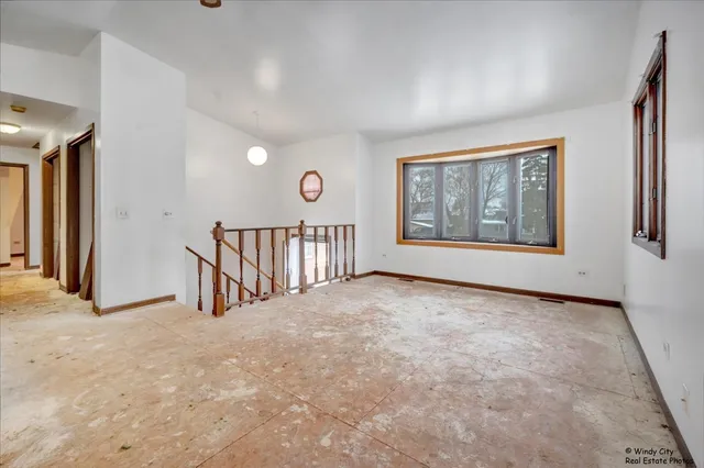 an empty room with windows and ceiling fan