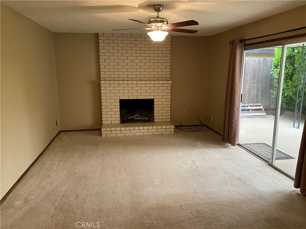 a view of an empty room with a fireplace and a ceiling fan