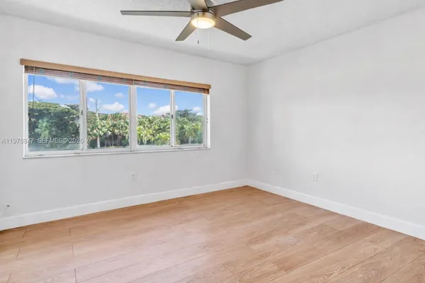 an empty room with a window and a ceiling fan