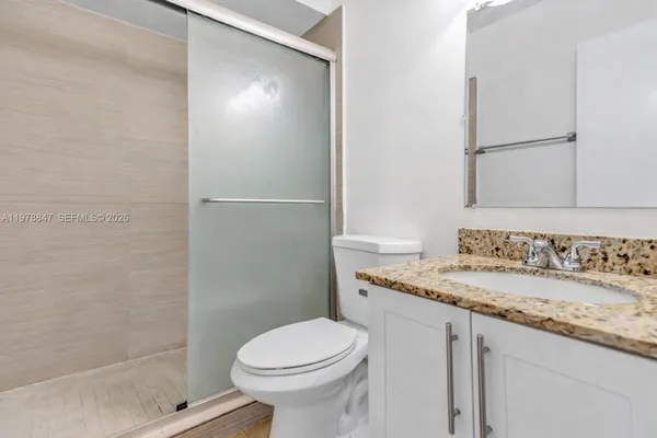a bathroom with a granite countertop sink toilet and shower