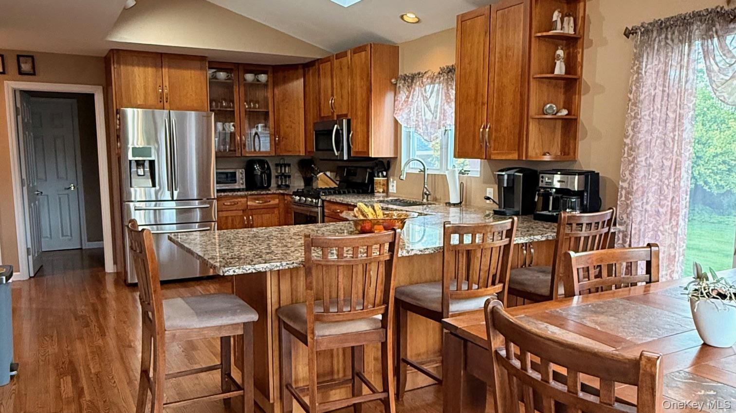 345 O'Connor Road North Babylon, NY 11703 - Photo 5 of 47 a kitchen with stainless steel appliances granite countertop a refrigerator a stove top oven and a dining table with wooden floor