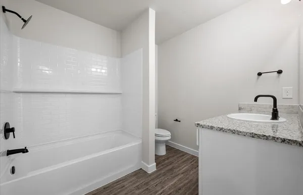 a bathroom with a granite countertop sink a toilet and bathtub