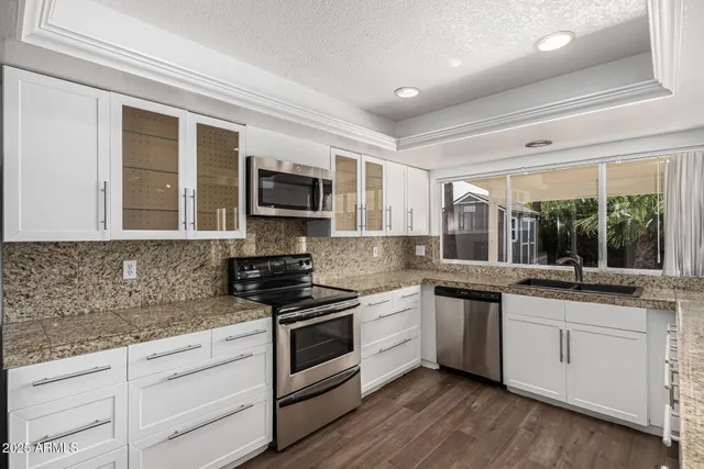 a kitchen with stainless steel appliances granite countertop a sink and stove top oven