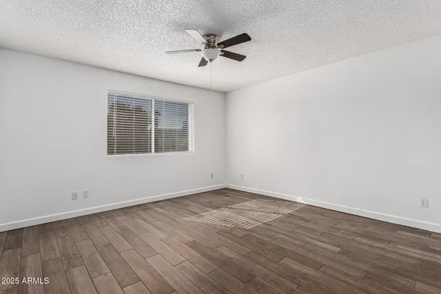 an empty room with wooden floor and a ceiling fan