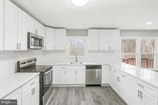 a kitchen with granite countertop a sink stainless steel appliances and white cabinets