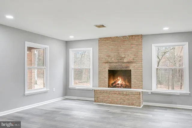 an empty room with windows and fireplace