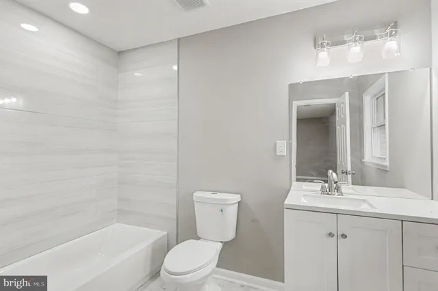 a bathroom with a bathtub shower sink vanity and toilet